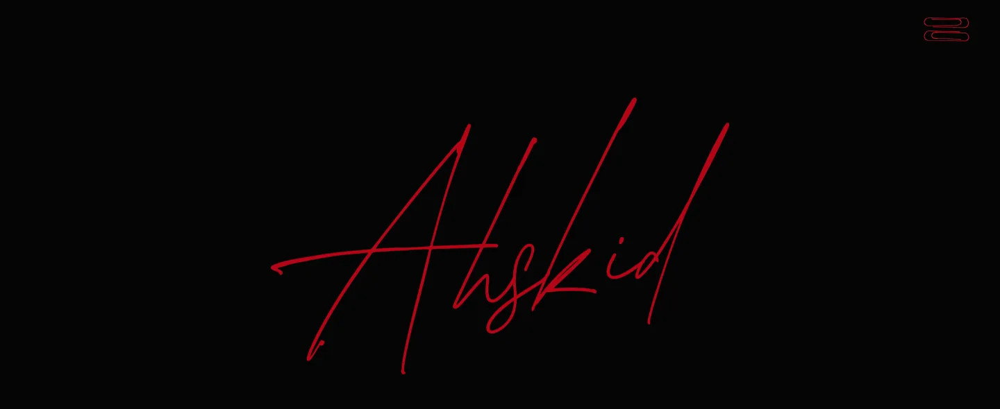 The home page opening: the Ahskid signature in red script across a black screen, with a pair of red paperclips in the top corner.