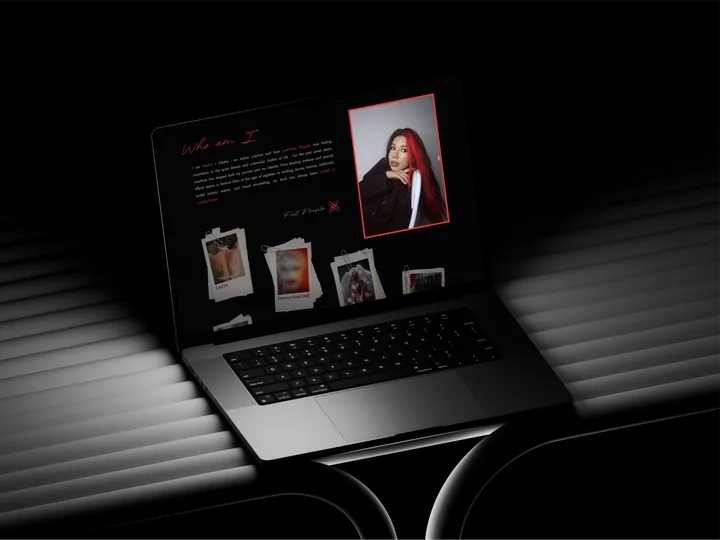 The Ahskid portfolio on a laptop in a dark room: a red-and-black “Who am I” page with Diksha’s portrait and pinned prints of the work.