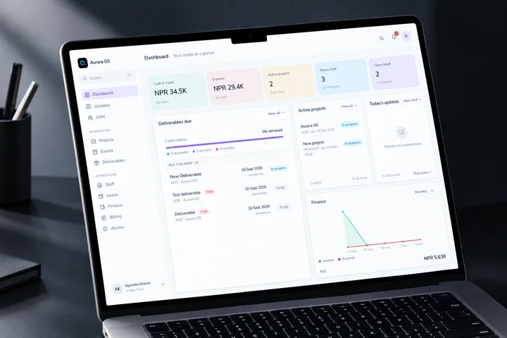 The Aurora OS dashboard on a laptop against a dark desk — cash in hand, active projects and staff across the top, deliverables due and a finance chart beneath.