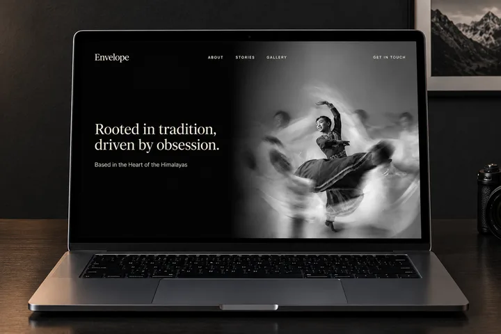 The Envelope about page on a laptop on a wooden desk — the headline beside a long-exposure photograph of a dancer mid-turn.