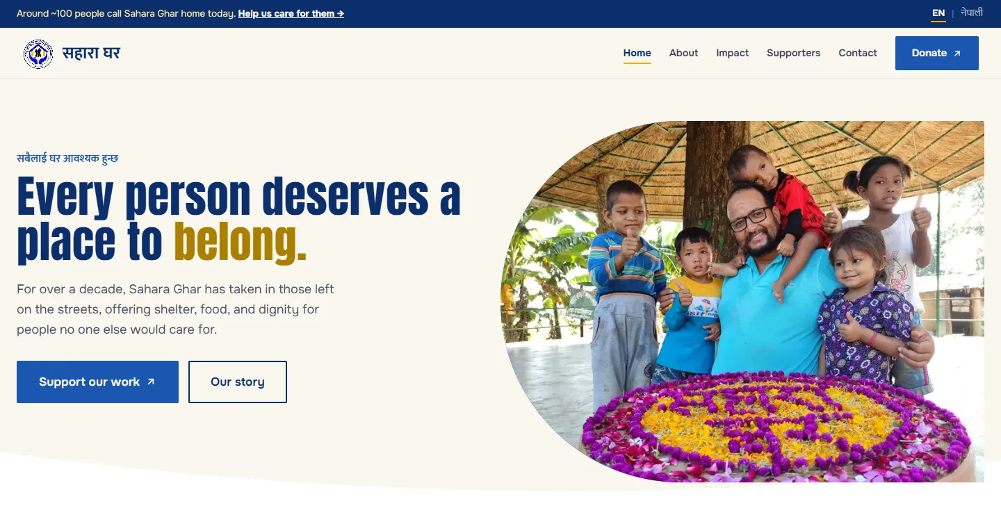 The Sahara Ghar home page: “Every person deserves a place to belong.” with “belong” in marigold, beside a photograph of the founder with children around a flower rangoli.